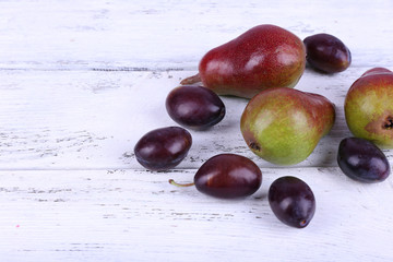 Beautiful ripe pears and plums on wooden table close-up