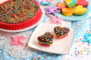 Delicious rainbow cakes on plates, on color wooden background