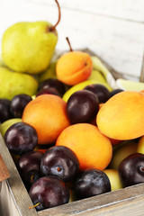 Ripe fruits in crate on wooden background