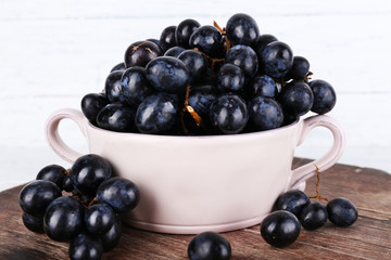 Purple grapes in bowl on wooden background