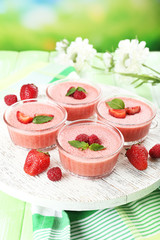 Delicious berry mousse in bowls on table on bright background