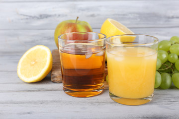 glasses of juice with fresh fruits on grey wooden table
