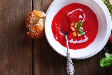 Gazpacho soup in spoon and bowl on  wooden background