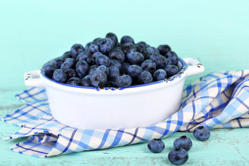 Tasty ripe blueberries in bowl, on wooden table