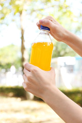 Hand opening bottle with sweet water on bright background