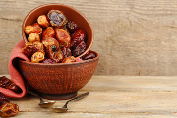 Tasty dates fruits in bowls, on wooden background
