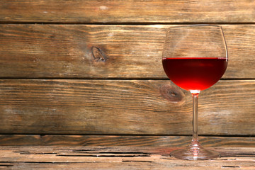 Glass of red wine on wooden table on wooden wall background
