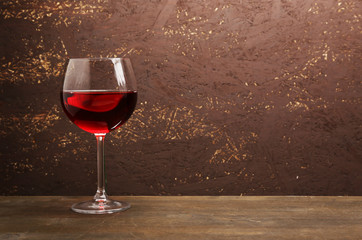 Glass of red wine on wooden table on wooden wall background