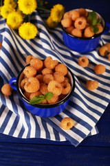 Yellow raspberries in dark blue mugs and wildflowers