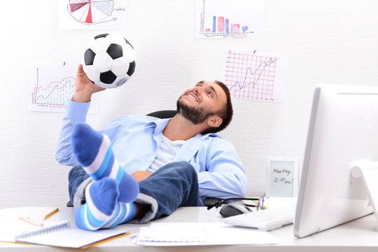 Confident Businessman Holding His Legs In Funny Socks On Desk