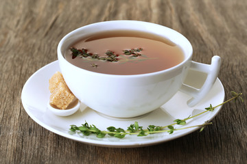 Cup of tasty herbal tea with thyme on wooden table