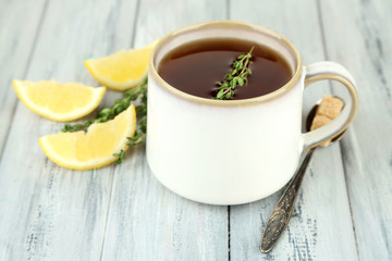 Cup of tasty herbal tea with thyme and lemon on wooden table