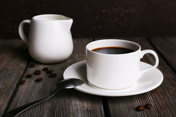 Cup of coffee with cream in milk jug and coffee beans