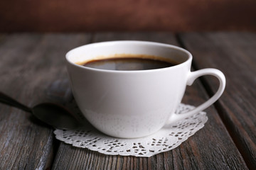 Cup of coffee on napkin on wooden background