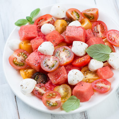 Salad with watermelon cubes, tomatoes, mozzarella balls and mint