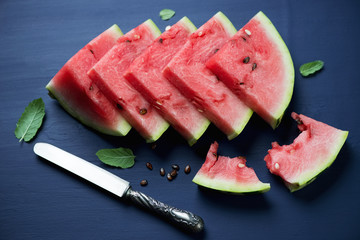 Sliced watermelon over dark blue wooden background, close-up