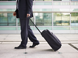 asian business traveler walking with suitcase