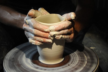 hands of a potter, creating an earthen jar on the circle