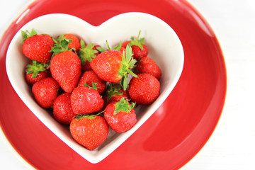 Heart shaped bowl of juicy red strawberries