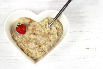Breakfast Oatmeal or Porridge in a heart shaped bowl. Rustic bac