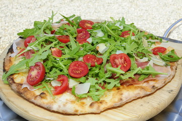 Pizza con pomodorini grana rucola e prosciutto crudo