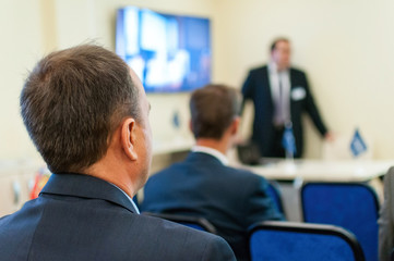 presenter near the screen and people sitting rear