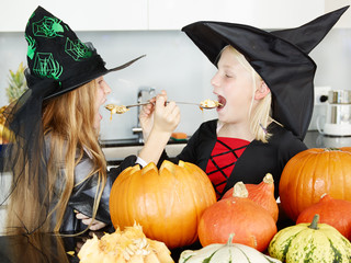 Little witches taste pumpkins in the kitchen