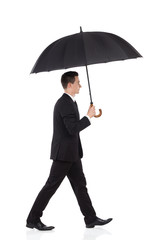 Businessman walking with an umbrella