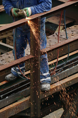 Welder using cutting torch to cut an old iron bridge