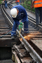 Welder using cutting torch to cut a rail