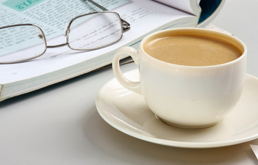 Cup of coffee near the laptop and newspapers