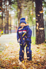 Naklejka premium Happy little boy throws the autumn leaves in the air.
