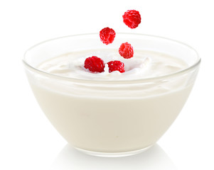 Delicious fresh raspberry falling into bowl of yogurt isolated