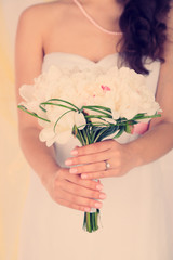 Bride holding wedding bouquet of white peonies, close-up,