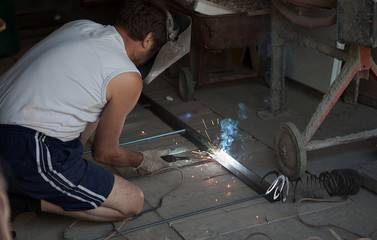 worker with protective mask welding metal and sparks