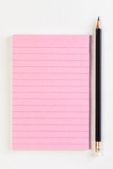 image of pink memo paper and black pencil on white backgound