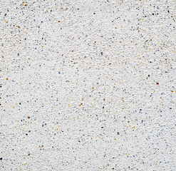 White cement wall with tiny rock on surface, grunge background.