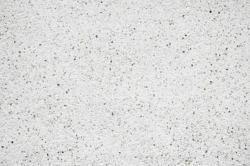 White cement wall with tiny rock on surface, grunge background.