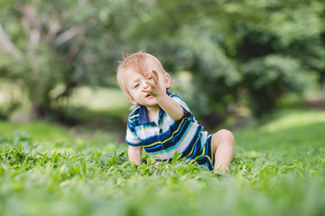 Cute little baby in summer park on the grass. Sweet baby outdoor
