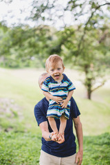 a little boy standing on his father, balancing