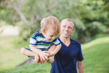 a little boy sitting on his father, balancing