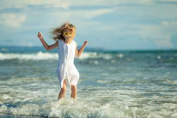 little girl standing on the beach at the day time