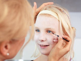 Mother paints the face of her girl