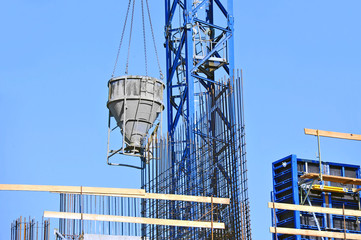 Crane lifting concrete mixer container against blue sky