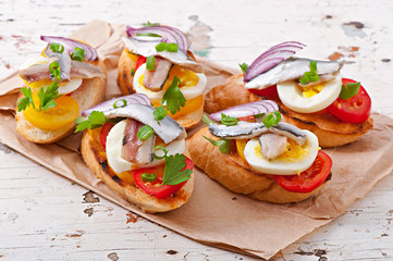 Crostini with anchovies, tomatoes and egg, decorated with greens