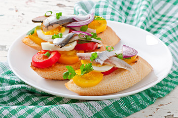 Crostini with anchovies, tomatoes and egg, decorated with greens