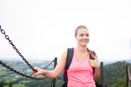 Young attractive woman/female tourist on the top of the hill/moutain/rock looking around on beautiful landscape (shallow DOF)
