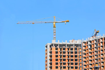 Fototapeta premium Crane and building construction site against blue sky