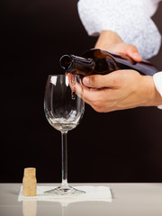 Man waiter pouring white wine into glass.