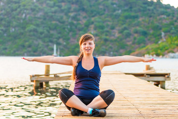 Fototapeta na wymiar relaxed girl on a pier in the lotus position